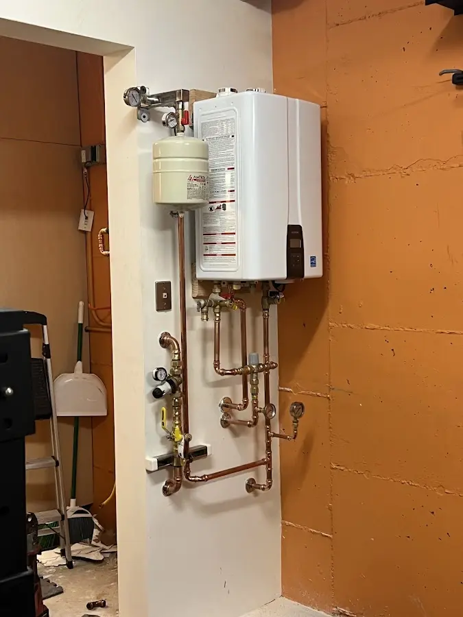 Plumbing technician inspecting water heater connections in Wheeling